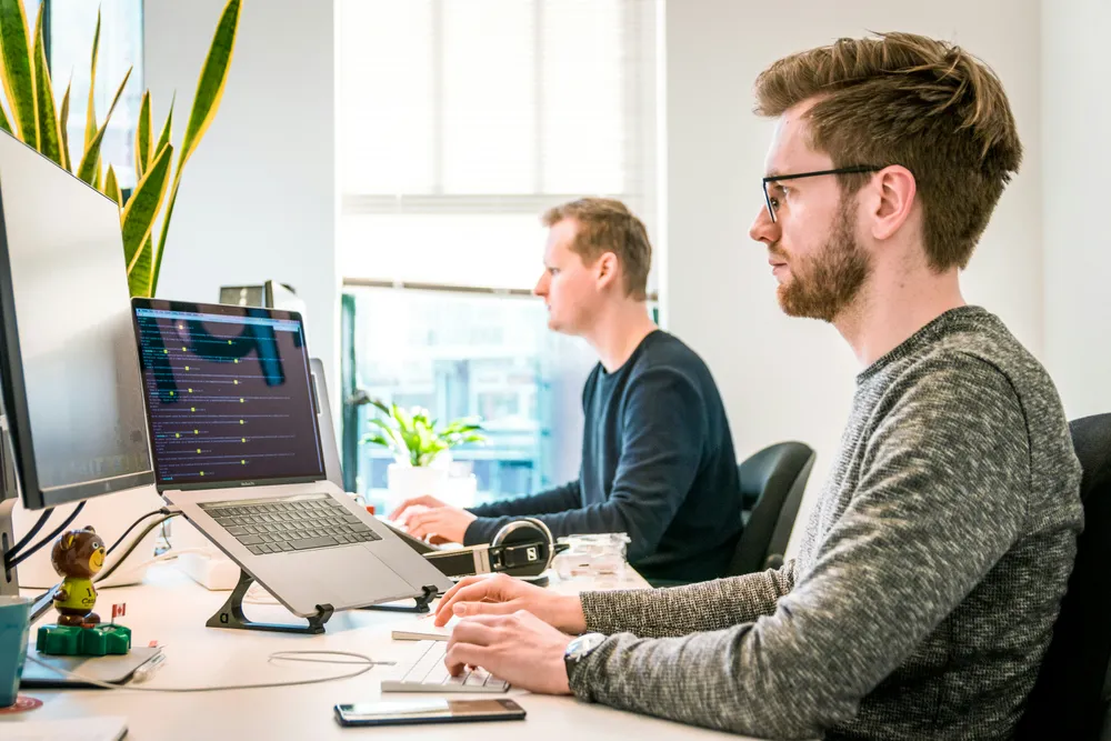 Två personer arbetar vid datorer på ett kontor